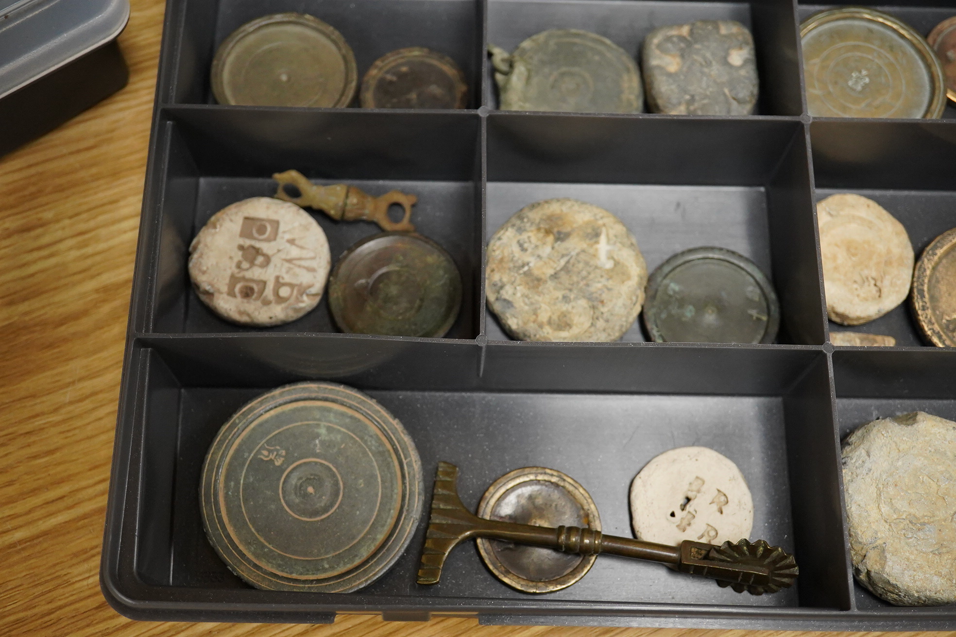 A collection of 16th century to 19th century bronze and lead circular trade weights, stamped with Royal Cyphers, weights, proof marks, the assay dagger for London, etc., contained within four plastic collector’s trays